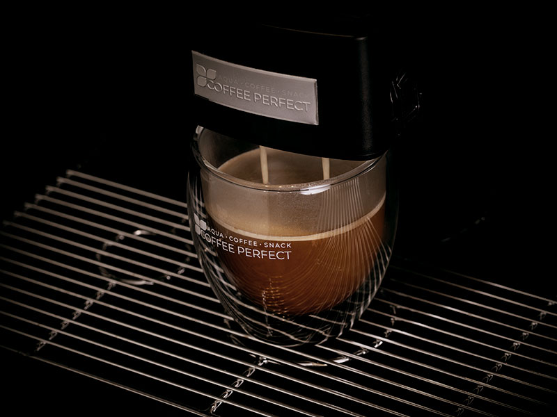 Tasse Kaffee unter einer laufenden Kaffeemaschine Tasse Kaffee unter einer laufenden Kaffeemaschine