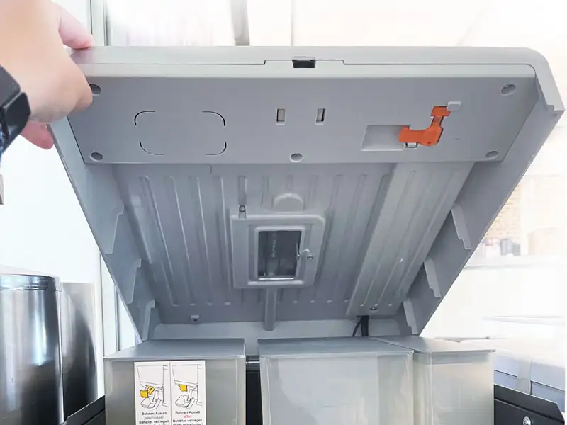 Geoeffneter Bohnenbehaelterdeckel eines Kaffeevollautomaten mit Blick ins Innere.