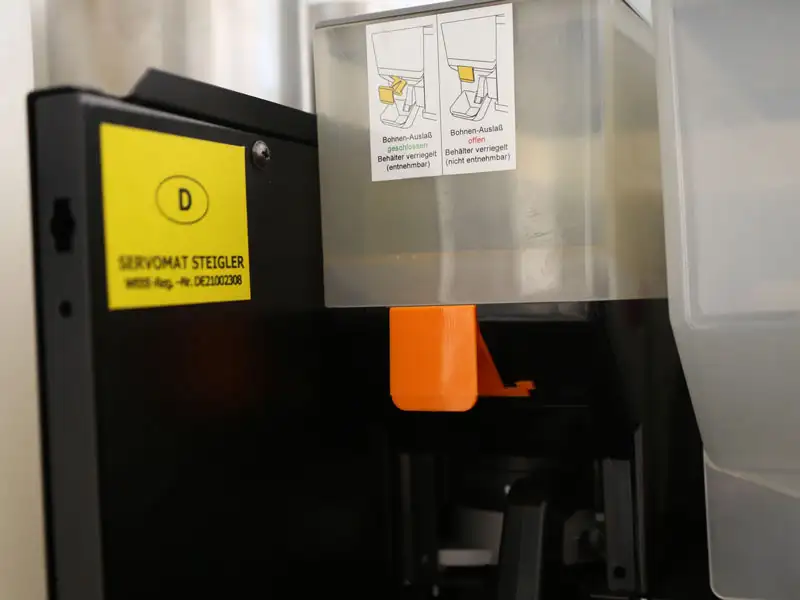 Bohnenbehaelter mit geschlossenem Auslass wird korrekt auf die Maschine gesetzt.