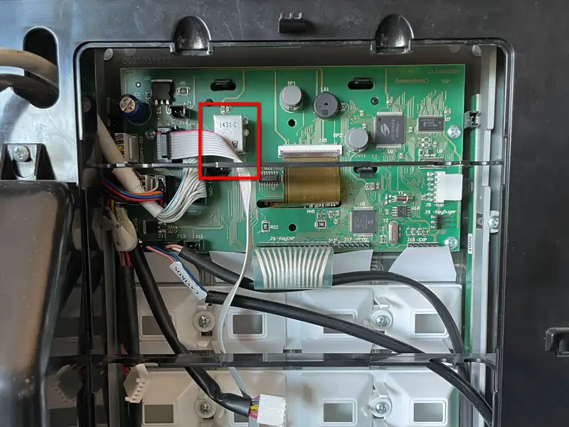 Finger drueckt die Servicetaste an der Rueckseite der orangen Innenabdeckung.