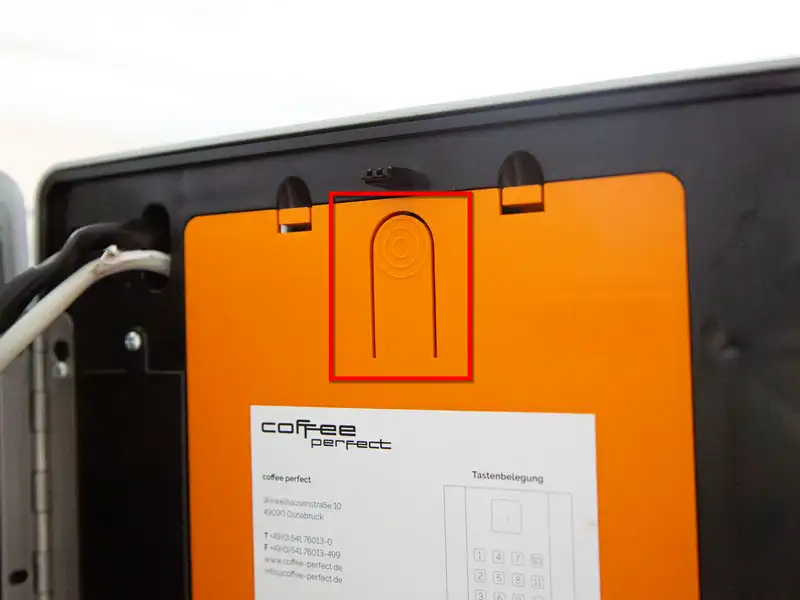 Orangene Programmtaste an der Innenseite der Kaffeemaschine wird hervorgehoben dargestellt.