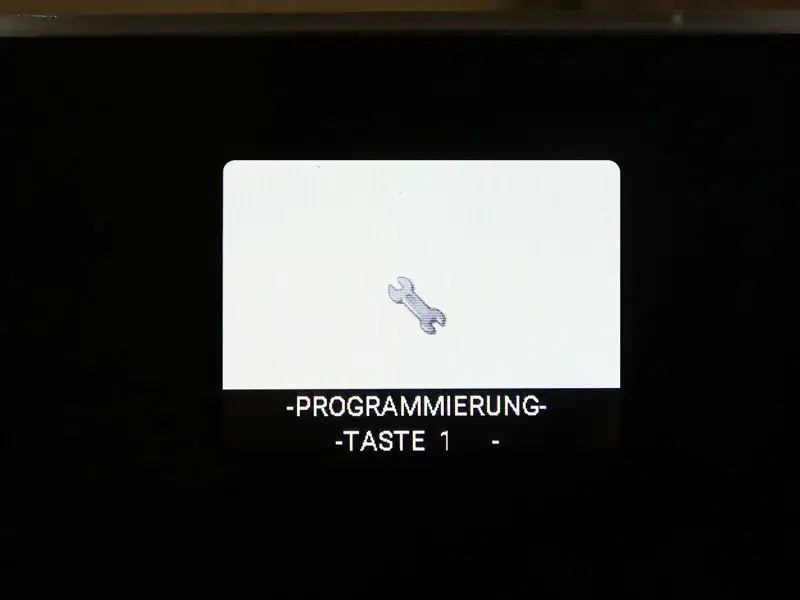 Display zeigt ein Schraubenschluesselsymbol mit der Anzeige 'PROGRAMMIERUNG - TASTE 1 -'.