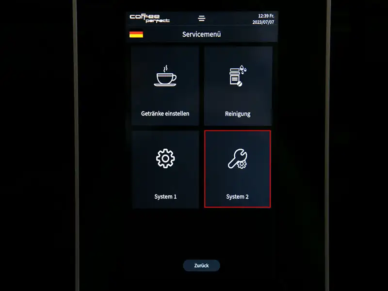 Display eines Kaffeevollautomaten mit hervorgehobener System-2-Option im Servicemenue.
