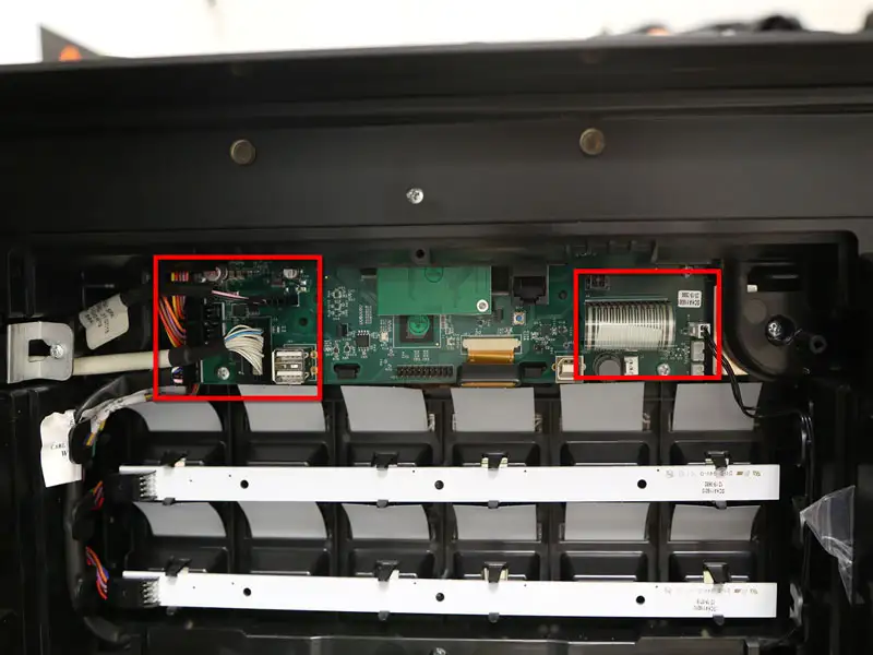 Innenansicht mit geoeffneter Abdeckung und markierten Steuerplatinen im oberen Bereich der Maschine.